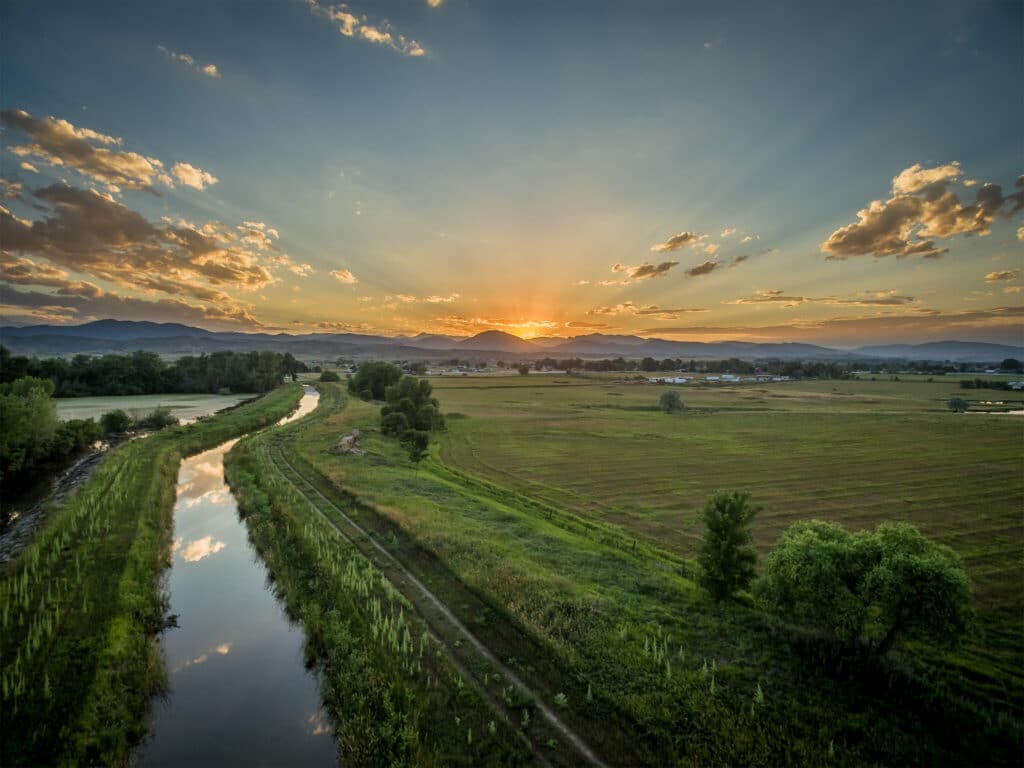 Water Canal And Field With Sunset