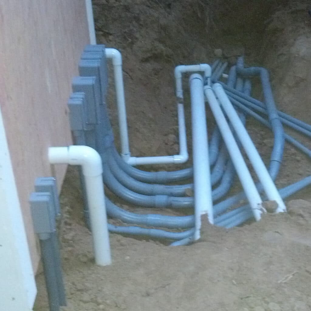 Water And Electrical Piping Leading From Wall To Trench