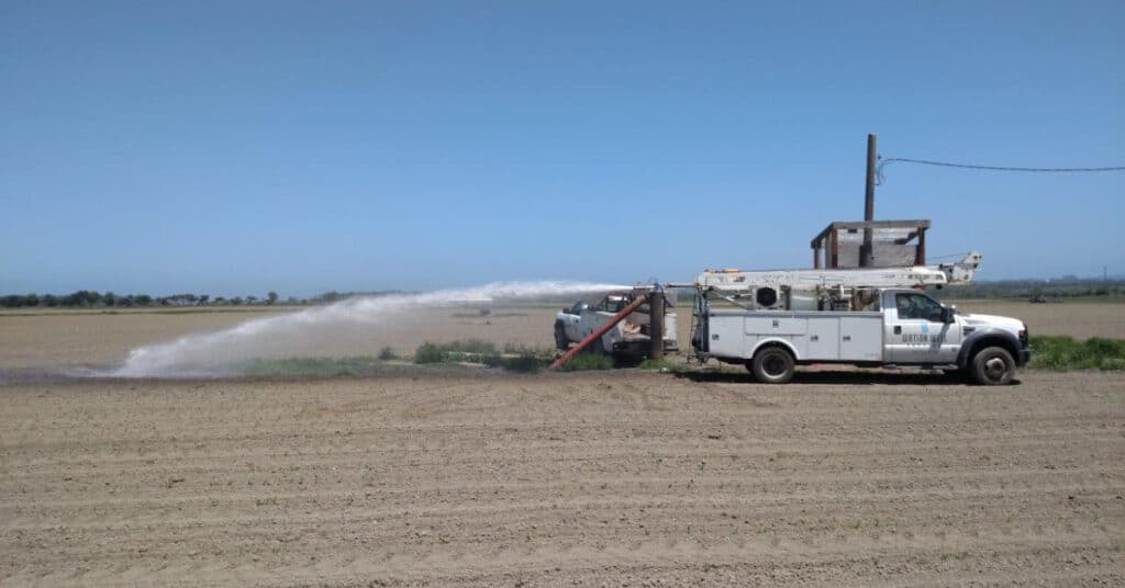 Truck Next To Well Head Releasing Water Into Field